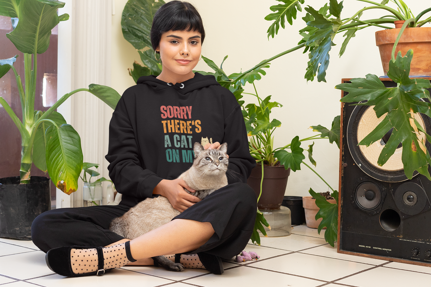 Woman wearing a hoodie with a cat on her lap